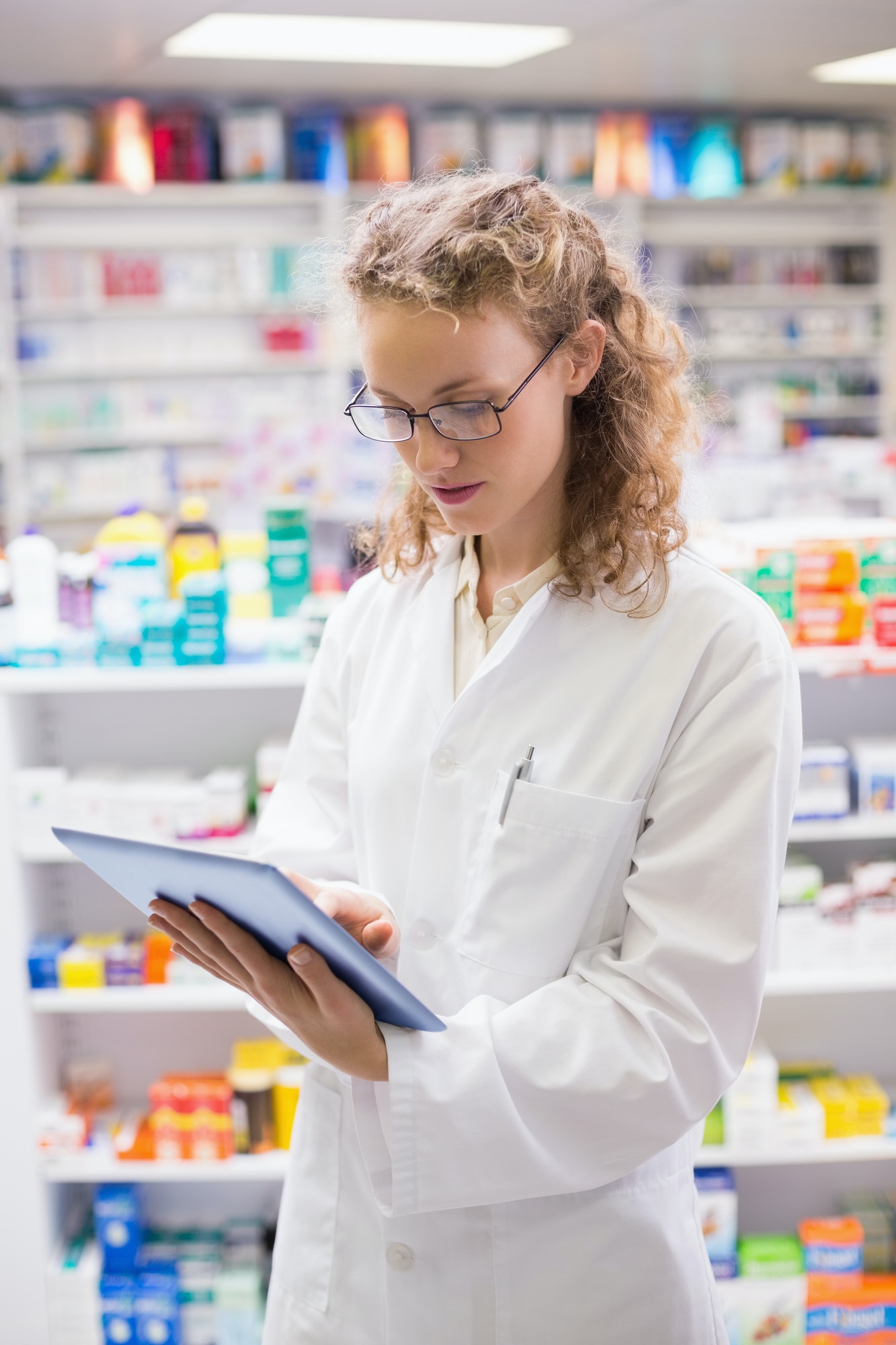 Female pharmacist checking medication inventory – local pharmacy service.